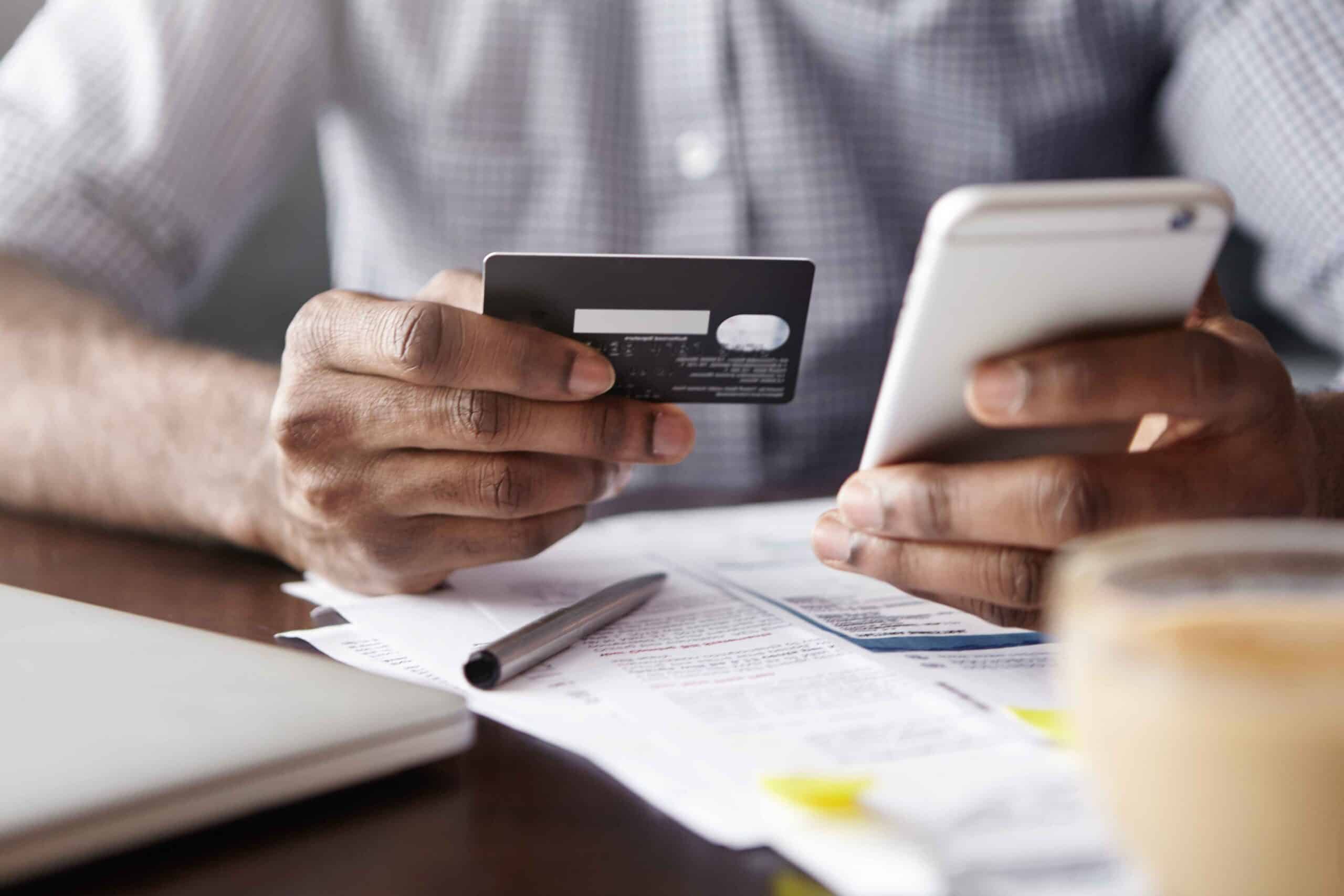 Person reviewing bills and making an online payment while applying for cash loans in Canada using a credit card and smartphone